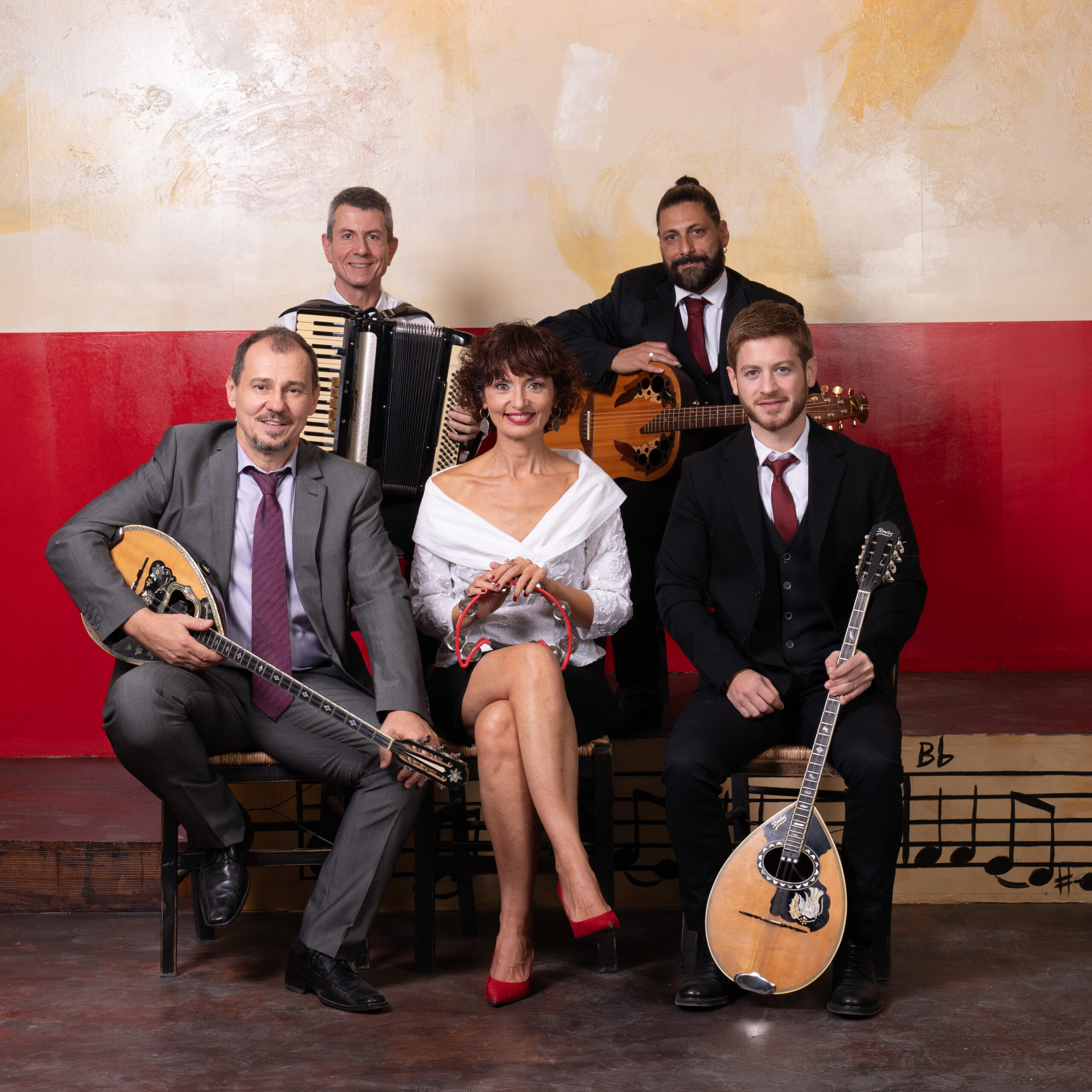The band seated on the stage, in front of the painted wall
