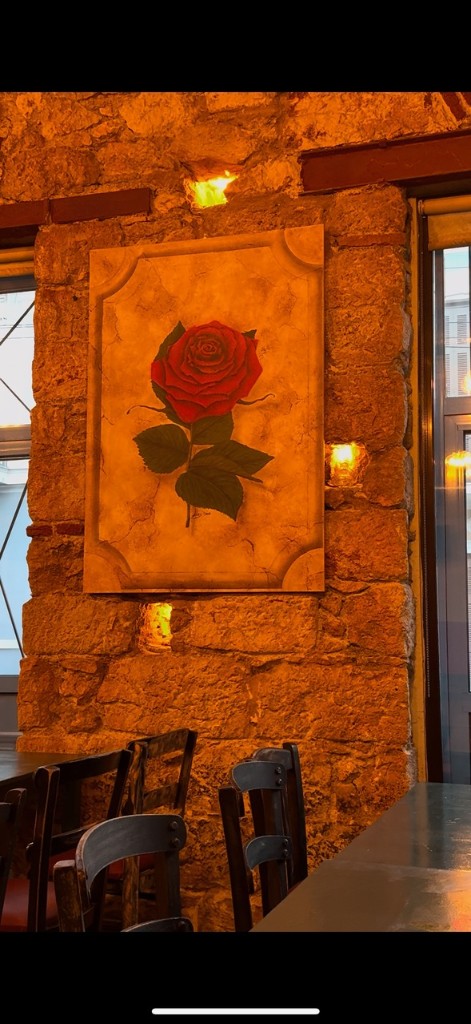 A framed red rose on the stone wall