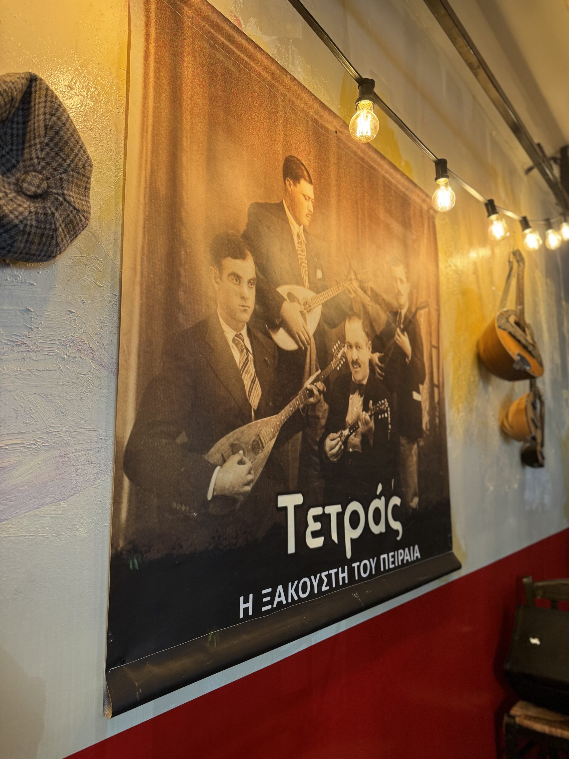 The poster of the Piraeus Tetras, with flat caps and baglamas hanging on the wall